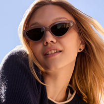 on model - blonde female wearing les do makeup x dime optics featuring last call cat eye sunglasses with a milky nude frame and brown with gold flash polarized lenses close up view