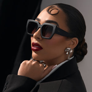 on model - rissa g wearing rissa g x dime optics she's a 10 square sunglasses with a glossy black frame with a dusk polarized lenses angled view