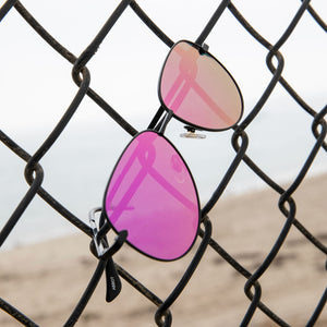 lifestyle - dime optics abbot in black with pink mirror hanging on a baseball cage 