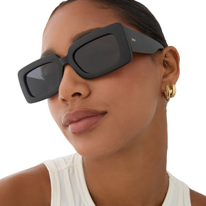 on model - female wearing dime optics featuring the culver rectangular sunglasses with a matte black frame and grey polarized lenses angled view