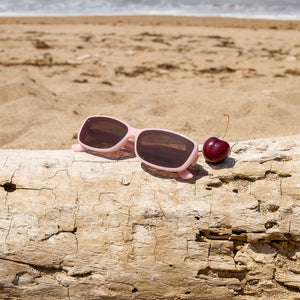 flat lay of dime optics featuring the agoura rectangular sunglasses with a candy heart pink frame and brown lenses top view