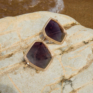 flat lay of dime optics alameda in gold sunglasses laying on the beach