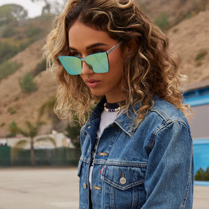 on model - female wearing dime optics glendale cat eye sunglasses with a crystal clear frame and cyan mirror lenses angled view