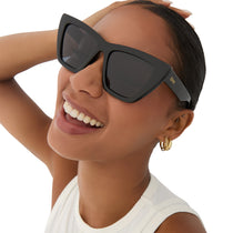 on model - female wearing dime optics featuring the windsor cat eye sunglasses with a black frame and grey polarized lenses angled view